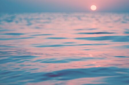 Blur tropical sunset beach with bokeh sun light wave abstract background. Travel concept. Retro color style.の写真素材