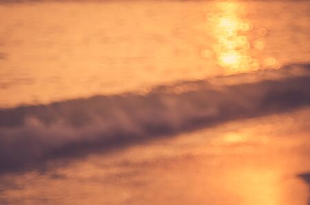 Blur tropical sunset beach with bokeh sun light wave abstract background. Copy space of outdoor summer vacation and travel adventure concept. Vintage tone filter color style.の写真素材