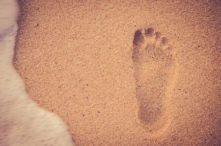 Sand beach foot print with smooth wave. Travel concept. Retro color style.の写真素材
