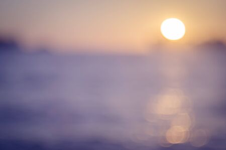 Blur tropical sunset beach with bokeh sun light wave abstract background. Copy space of outdoor summer vacation and business travel concept. Vintage tone filter color style.の写真素材