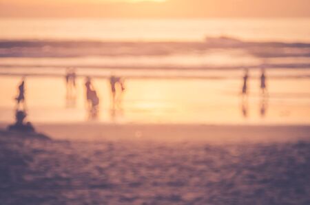Blur people relax on tropical sunset beach with bokeh sun light wave abstract background. Copy space of summer vacation and business travel concept. Vintage tone filter color style.の写真素材