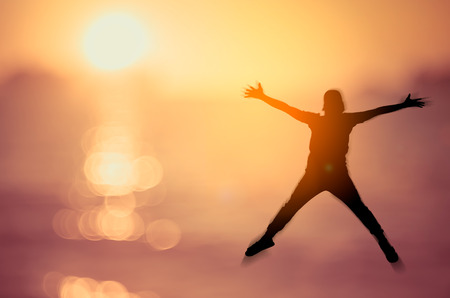 Feel good and freedom concept. Copy space of silhouette happy man jumping on tropical sunset beach. Vintage tone filter color style.の写真素材