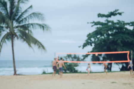 Blur people play volleyball on sand beach with palm tree abstract background. Copy space of summer vacation travel and sport exercise concept. Vintage tone filter color style.の写真素材