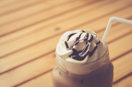 Ice coffee on wood table background. Shallow dept of field. Drink background concept. Retro color style.の写真素材