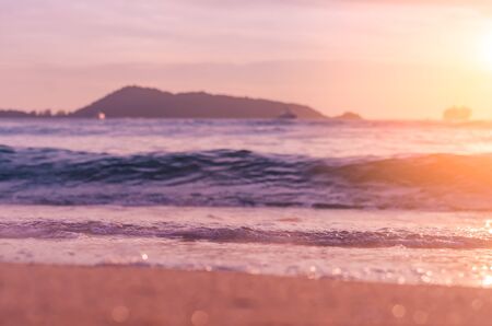 Blur tropical sunset beach with bokeh sun light wave abstract background. Copy space of outdoor summer vacation and travel adventure concept. Vintage tone filter color style.の写真素材