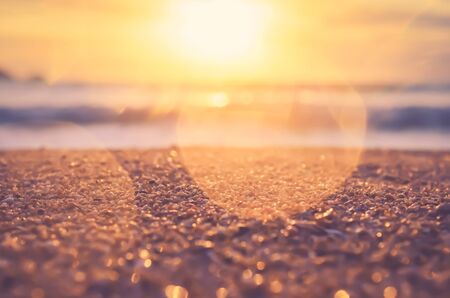 Blur tropical sunset beach with bokeh sun light wave abstract background. Copy space of outdoor summer vacation and travel adventure concept. Vintage tone filter color style.の写真素材