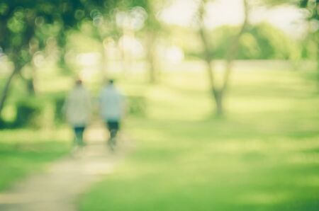 Blur people walking in nature green park with sun light copy space abstract background. Travel and...