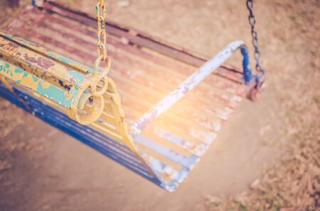 Close up old iron swing playground in outdoor park. Copy space of sport exercise and health care concept. Shallow depth of field. Vintage tone filter color style.の写真素材