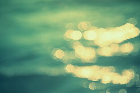 Blur tropical sunset beach with bokeh sun light wave abstract background. Copy space of outdoor summer vacation and business travel concept. Vintage tone filter color style.の写真素材