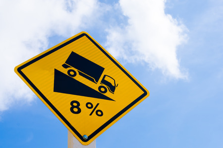 Traffic sign. Down hill sign warning on blue sky and white cloud background. Copy space of transportation and travel concept.の写真素材