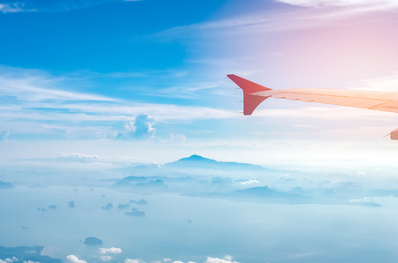 Airplane window view over sea and island with blue sky and white cloud abstract background. Copy space transportation and business travel adventure concept.の写真素材