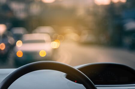 Inside car view ,steering wheel on blur traffic road with colorful bokeh light abstract background. Copy space of transportation and travel concept. Vintage tone filter effect color style.の写真素材