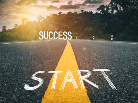 Start  and success words on yellow line on country road in storm cloud and mountain background. Travel adventure and transportation concept. Retro tone filter effect color style.の写真素材