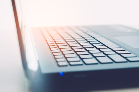 Business economic and technology working concept. Close up keyboard notebook with window light bokeh abstract background. Shallow depth of field. Vintage tone filter effect color style.の写真素材