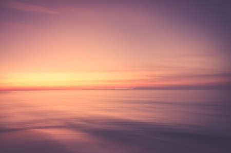 Motion blur tropical sunset beach with bokeh light wave abstract background. Copy space of summer vacation and business travel adventure concept. Vintage tone filter effect color style.の写真素材