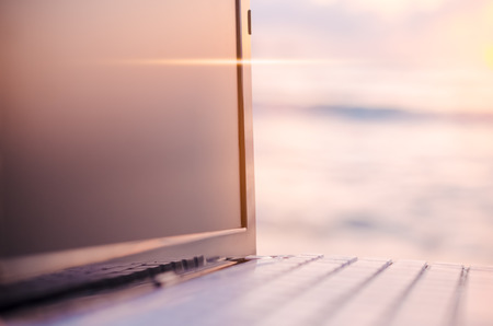 Copy space business economic technology working and travel adventure lifestyle concept. Keyboard notebook on tropical sunset beach background. Shallow depth of field. Vintage filter effect color styleの写真素材