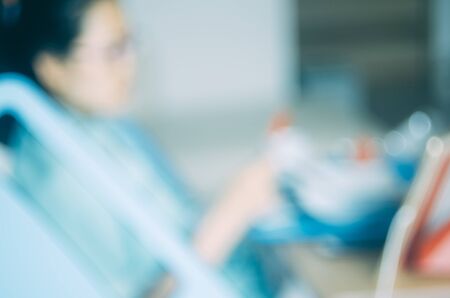 Blur patient woman eating food on bed in hospital abstract background. Copy space of health care and food drink concept. Vintage tone filter effect color style.の写真素材