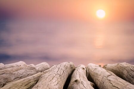 Blur beautiful tropical sunset beach with bokeh light wave on copy space empty old wood table abstract background. Product presentation in fresh nature. Vintage tone filter effect color style.の写真素材