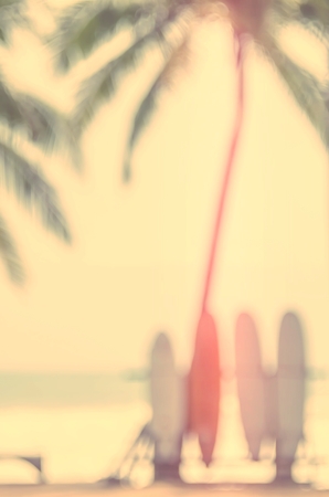 Blur colorful surfboard and palm leaf on tropical island beach abstract background. Copy space of summer vacation and extreme water sport concept. Retro tone filter color style.の写真素材