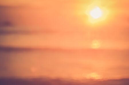 Blur tropical sunset beach with bokeh sun light wave abstract background. Copy space of outdoor summer vacation and travel adventure concept. Vintage tone filter color style.の写真素材