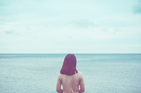 Feeling sad mood concept. Copy space of loneliness woman looking view of beach background. Vintage tone filter effect color style.の写真素材