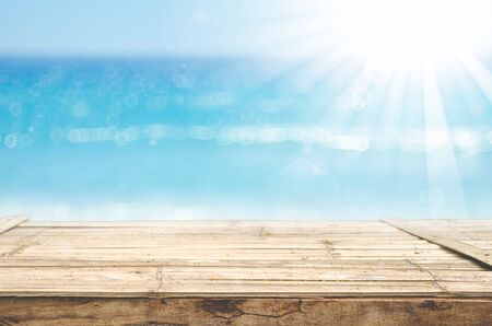 Blur tropical beach with bokeh sun light wave on empty old wood table abstract background. Product presentation in nature. Vintage tone filter color style.の写真素材