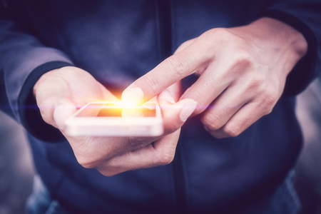 Close up man hand hold using smart phone on outdoor park street background. Copy space of technology business and travel holiday concept. Vintage tone filter effect color style.の写真素材