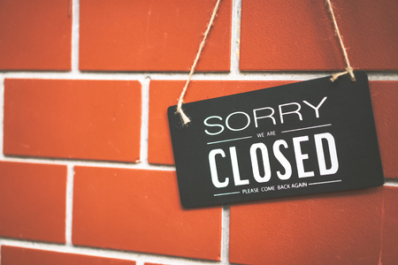 Close sign hanging on brown stone wall texture background. Business and service concept.の写真素材
