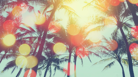 Tropical palm tree with colorful bokeh sun light on sunset sky cloud abstract background. Summer vacation and nature travel adventure concept. Vintage tone filter effect color style.の写真素材