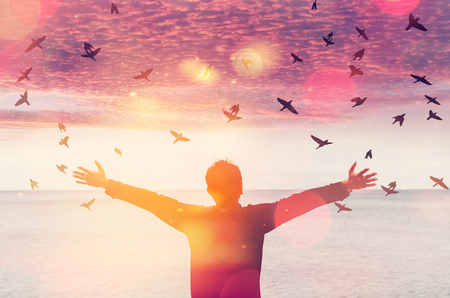 Copy space of man rise hand up on sunset sky at beach and island double exposure bird fly colorful bokeh abstract background. Freedom and travel adventure concept. Vintage tone color style.の写真素材