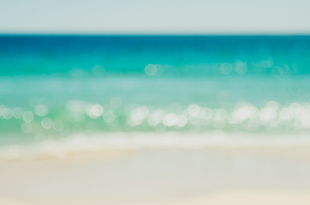 Blur tropical beach with bokeh sun light wave abstract background. Copy space of outdoor summer vacation and travel adventure concept. Vintage tone filter effect color style.の写真素材