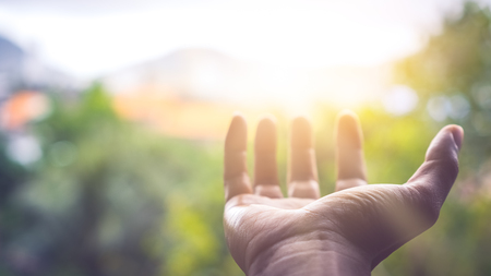 Close up man hand open with sun light on green nature bokeh and blur city abstract background. Copy space for technology business and lifestyle  concept. Vintage tone filter effect color style.の写真素材