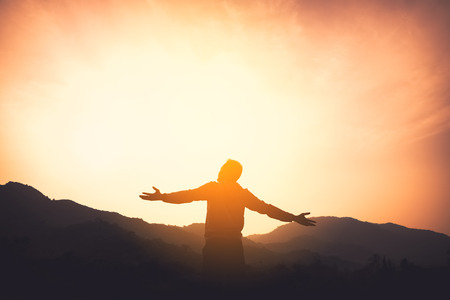 Copy space of man rise hand up on top of mountain and sunset sky abstract background. Freedom and travel adventure concept. Vintage tone filter effect color style.の写真素材