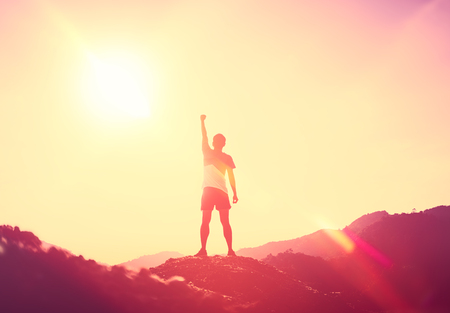 Copy space of man hand raising on top of mountain and sunset sky abstract background. Freedom travel adventure and business victory concept. Vintage tone filter effect color style.の写真素材