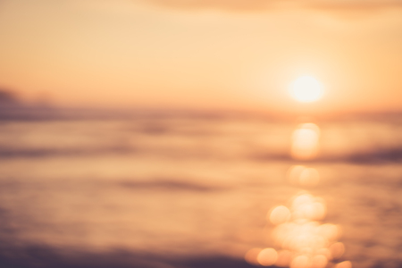 Blur tropical sunset beach with bokeh sun light wave abstract background. Copy space of outdoor summer vacation and travel adventure concept. Vintage tone filter color style.の写真素材