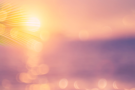 Blur beautiful nature green palm leaf on tropical sunset beach with bokeh light wave abstract background. Copy space of summer vacation and business travel concept. Vintage tone filter color style.の写真素材