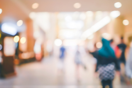 Blur people walking in shopping center mall abstract background. Copy space of business travel concept. Retro tone filter color style.の写真素材