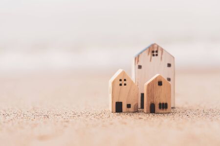 Small home model on sunset beach sand texture background. Copy space of family lifestyle and business real estate concept. Vintage tone filter effect color style.