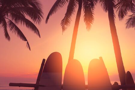 Surfboard and palm tree on tropical sunset beach background. Travel adventure sport and summer...
