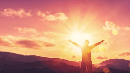 Copy space of man hand raising on top of mountain and sunset sky abstract background. Freedom travel adventure and business victory concept. Vintage tone filter effect color style.の写真素材
