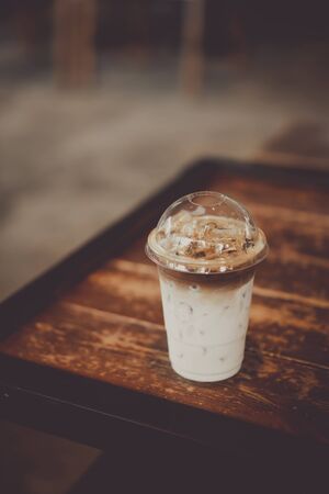 Ice coffee on wood table in cafe shop. Food and drink concept. Vintage tone color style.の写真素材