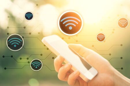 Woman hand using smart phone at outdoor nature park and sunset sky with wifi icon line abstract...