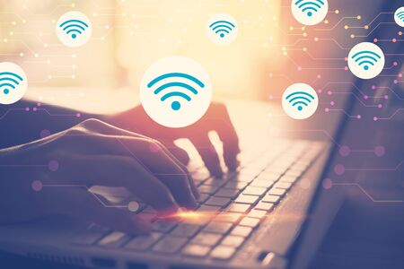 Business economic technology and working connect concept. Close up woman hand using laptop with wifi icon flying and colorful bokeh background. Vintage tone filter effect color style.の写真素材