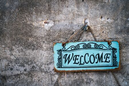 Welcome sign board hanging on stone wall texture background. Business and symbol concept.の写真素材