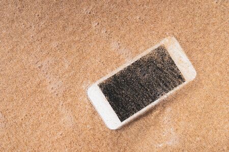 Smart phone on tropical sand beach texture background. Black copy space of technology business and...