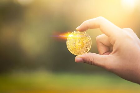 Man hand holding bitcoin at outdoor park background. Economy financial and business concept.