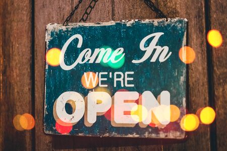 Open sign hanging front of cafe with colorful bokeh light abstract background. Business service and...