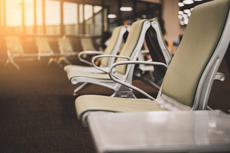 Empty chair in airport terminal gate with window sunset light background. Travel adventure and vacation freedom concept. Vintage tone filter effect color style.の写真素材