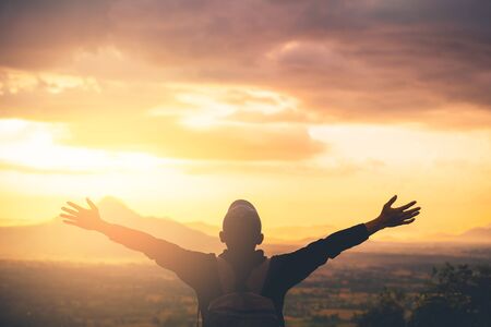 Backpacker man raise hand up on top of mountain with sunset sky and clouds abstract background. Copy...