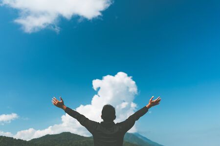 Copy space of man hand raising on top of mountain and blue sky white cloud background. Freedom...